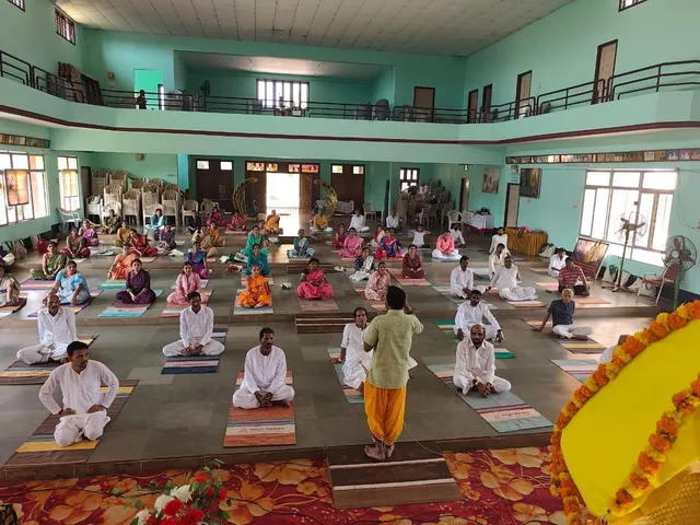 Participants practising seated yoga in a community hall in Honnavara