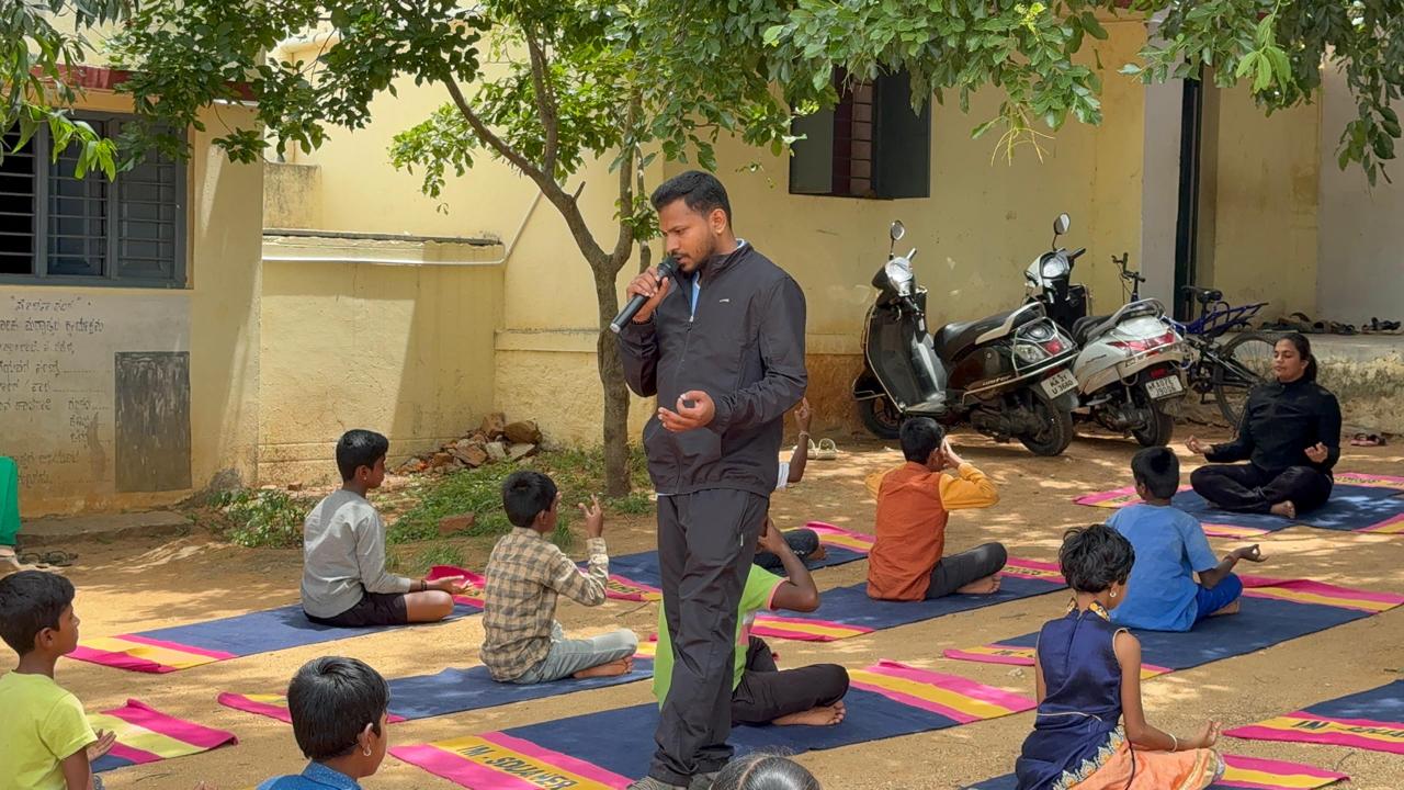 Nikhil guiding children through an outdoor school yoga session